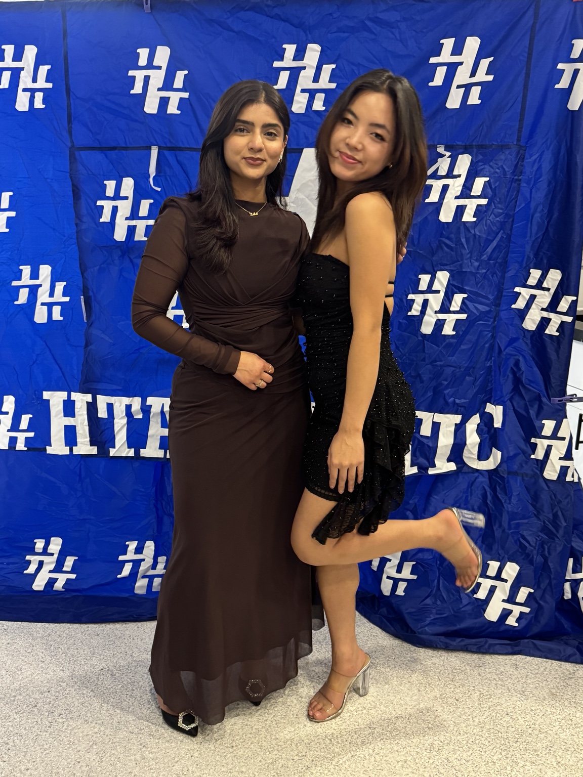 Two guests posing in front of an HT Athletic backdrop