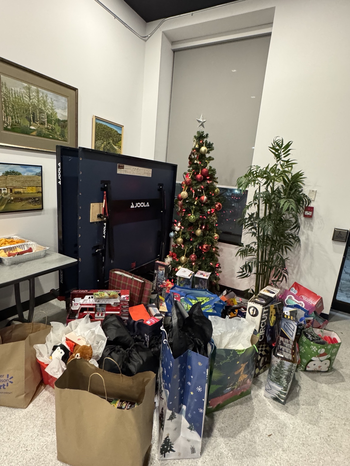 Gifts and donated items beside a Christmas tree