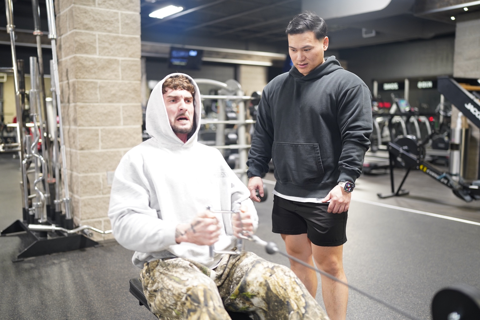Coach supporting a client during a seated cable row